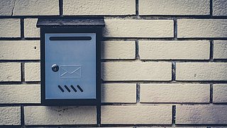 Foto, Nahaufnahme eines Hausbriefkastens an einer hellen Ziegelwand.