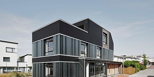 Foto, Außenansicht von modernem Einfamilienhaus mit dunkler Fassade und asymmetrischer Form.