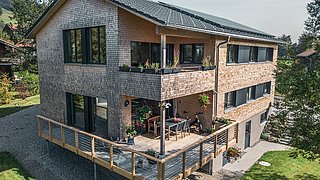 Foto, Außenansicht auf Zweifamilienhaus mit Terrasse, Balkon und Photovoltaik-Kollektoren auf dem Dach.