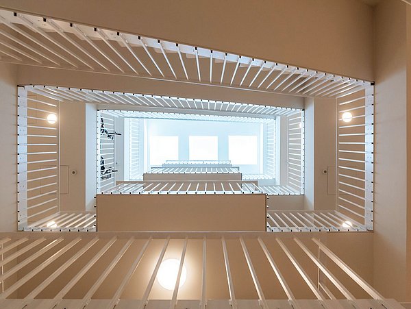 Foto, Perspektive von unten nach oben in einen hellen Treppenhausschacht.