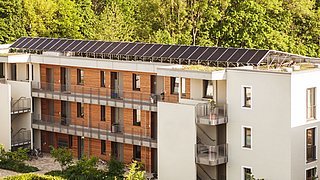 Foto, ein modernes mehrstöckiges Wohngebäude mit einer Photovoltaikanlage auf dem Dach.