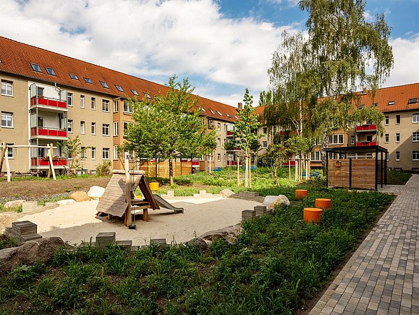 Foto, Innenhof eines Mehrfamilienhauses mit Spielplatz und Sandkasten