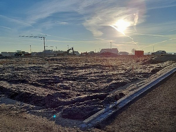 Foto, Panoramabild einer Baustelle. In der Ferne stehen Kräne vor einem blauen Himmel.