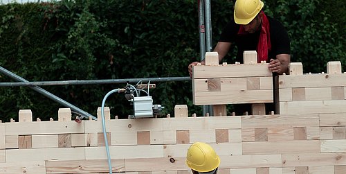 Foto, Arbeiter montieren eine Wand aus einem modularen Holzbausystem.