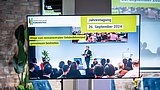 Foto, großer Bildschirm mit dem Bild eines Vortrags bei der Jahrestagung des Gebäudeforum Klimaneutral 2024