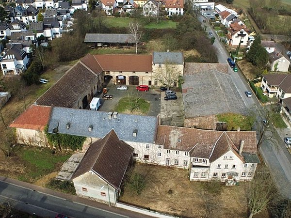 Foto, Luftaufnahme eines historischen Gehöfts mit mehreren Gebäuden und einem Innenhof in einer Wohnsiedlung
