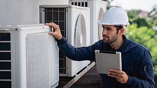 Foto, Ein Techniker mit Schutzhelm inspiziert mit einem Tablet in der Hand Klimaanlagen.