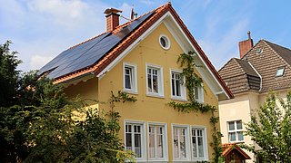 Foto, Blick auf ein hochwertig saniertes Einfamilenhaus mit einer Photovoltaikanlage auf dem Dach.