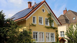 Foto, Blick auf ein hochwertig saniertes Einfamilenhaus mit einer Photovoltaikanlage auf dem Dach.
