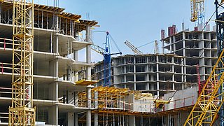 Foto, Blick auf eine Baustelle mit mehreren mehrstöckigen Gebäuden im Rohbau, die gerade errichtet werden.