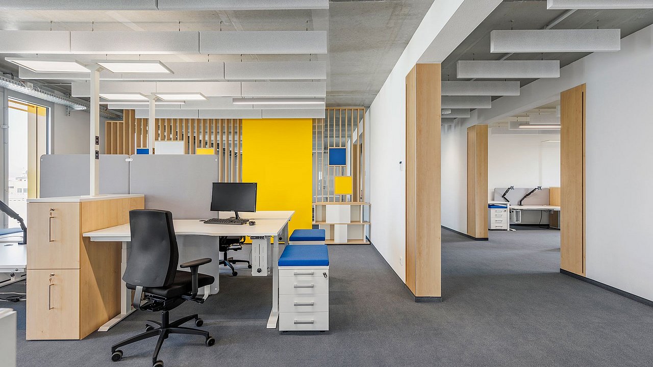 Foto, offener Büroraum mit Raumtrennern und Arbeitsplätzen.