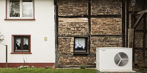 Foto, Teilansicht eines Hauses mit Fachwerkfassade mit Außentechnik einer Wärmepumpe