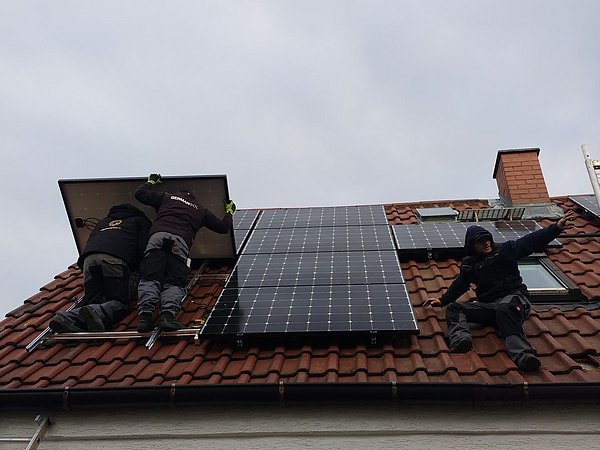 Foto, Arbeiter installieren die Photovoltaikanlage auf dem Dach des Einfamilienhauses.