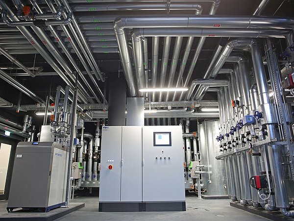 Foto, Anlagenraum mit Anlagentechnik und Leitungen an der Decke