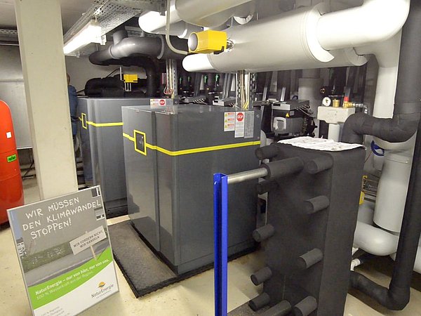Foto, Wärmepumpenanlage in einer Technikzentrale mit Rohren und Schildern