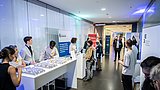 Foto, Personen an einem Informationsstand mit Modellen und Bannern bei einer Veranstaltung in einem Flur