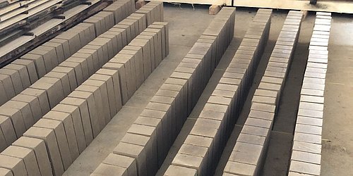 Foto, zum Trocknen aufgereihte Lehmbausteine