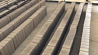 Foto, zum Trocknen aufgereihte Lehmbausteine