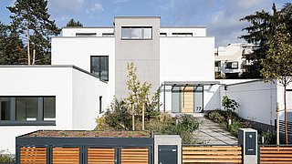 Foto, Straßenansicht auf ein modernen Einfamilienhaus mit großem Holztor im Vordergrund