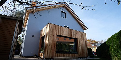 Foto, Außenansicht des Einfamilienhauses mit teilweiser Holzverkleidung. 