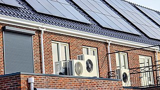 Foto, Häuserzeile mit Wärmepumpen davor und Solar-Modulen auf dem Dach