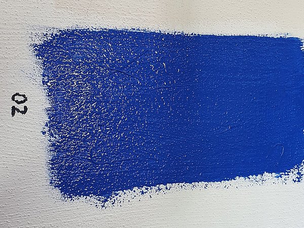 Leuchtend blauer Farbstrich mit 02 beschriftet auf weißem Untergrund, Farbmuster, Kaolinfarbe