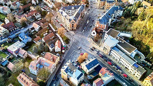 Foto, Luftaufnahme eines belebten Straßenkreuzes in einer Stadt mit Wohn- und Geschäftsgebäuden und Fahrzeugen auf den Straßen