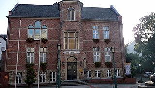 Foto, Rathaus mit Klinkerfassade und Türmchen in der Mitte des Gebäudes.