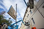 Foto, Bauarbeiten an einer Hausfassade. Mit einer Hebebühne wird ein Fassadenelement zum Haus befördert.