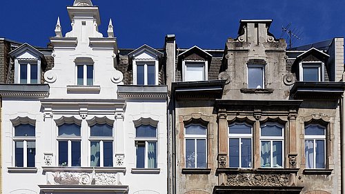 Foto, ein sanierter und ein unsanierter mehrstöckiger Altbau ähnlichen Typs nebeneinander.