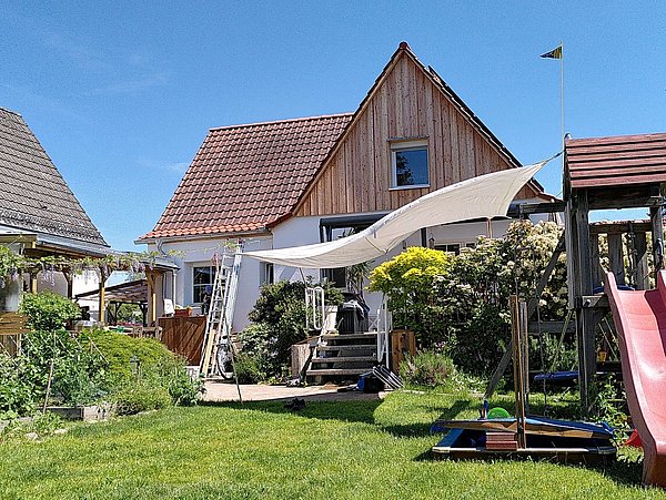 Foto, Einfamilienhaus mit Garten, Klettergerüst und Rutsche. 