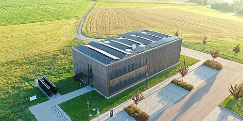 Foto, Luftaufnahme der Forschungshalle in Feuchtwangen mit Photovoltaik-Modulen auf dem Dach.
