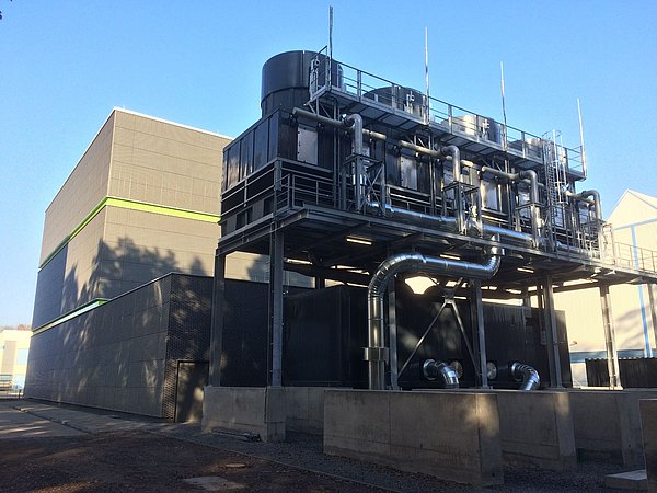 Foto, Industrieanlage mit großen schwarzen Rohren und technischen Geräten auf einem Betonfundament