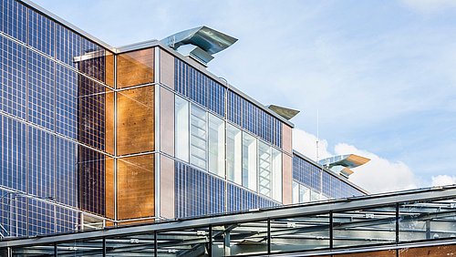 Foto, Gebäudefassade mit großen Solarpaneelen unter blauem Himmel.