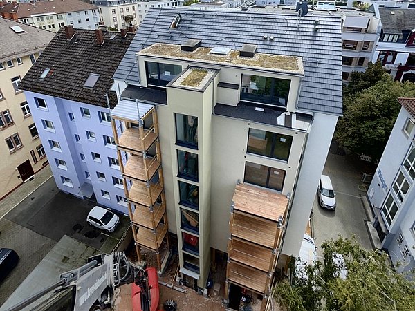 Foto, Luftaufnahme eines Mehrfamilienhauses und dessen Hinterhof, in dem Balkone an dem Gebäude angebracht werden