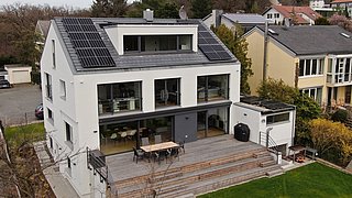 Foto, saniertes Einfamilienhaus mit geräumiger Terasse und Photovoltaikanalge auf dem Dach. 