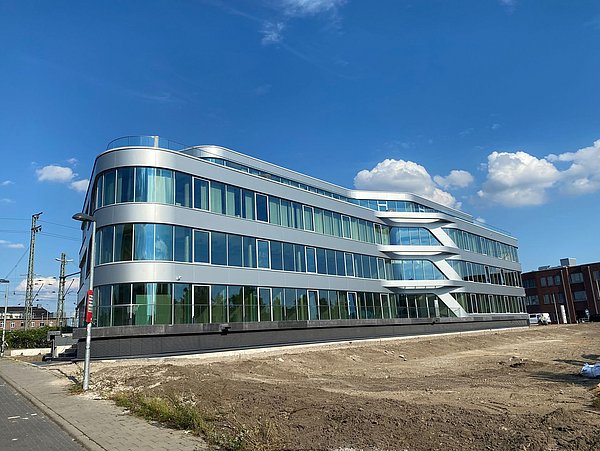 Foto, Außenaufnahme eines modernen Gebäudes mit Fassade in Silber und großen Fensterflächen.