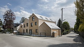 Foto, Modernes Wohnhaus mit dreieckigen Dachformen und Holzfassade an einer Straßenecke in einer Wohngegend