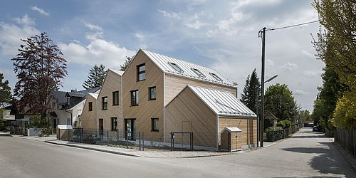 Foto, Modernes Wohnhaus mit dreieckigen Dachformen und Holzfassade an einer Straßenecke in einer Wohngegend
