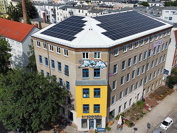 Foto, Dreigeschossiges Gebäude mit Solarpaneelen auf dem Dach und Graffiti an der Fassade in einer Wohngegend