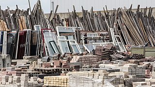 Foto, ein Bauhof mit gebrauchten Ziegelsteinen, Fenstern und anderen Baumaterialien und Bauteilen.