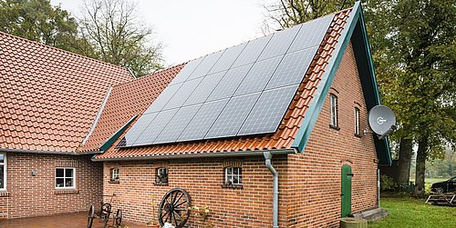 Foto, Außenansicht eines Niedersachsenhauses mit Photovoltaik-Kollektoren auf dem Dach.