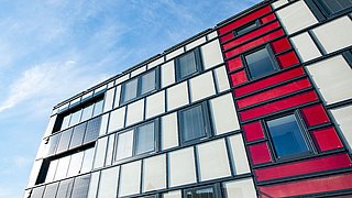 Foto, Hausfassade von unten nach oben aufgenommen vor blauem Himmel.