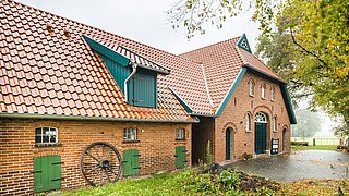 Foto, Außenansicht eines Niedersachsenhauses mit Klinkerfassade und grünen Details.