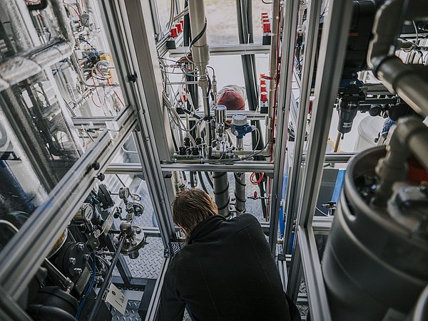 Foto, Mann steht in einem Glaskasten mit Anlagentechnik