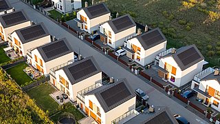 Foto, Luftaufnahme einer Wohnsiedlung mit mehreren modernen Einfamilienhäusern, die auf den Dächern mit Solarpaneelen ausgestattet sind.