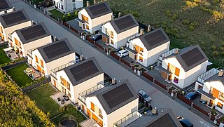 Foto, Luftaufnahme einer Wohnsiedlung mit mehreren modernen Einfamilienhäusern, die auf den Dächern mit Solarpaneelen ausgestattet sind.