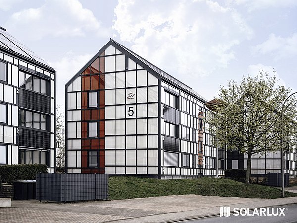 Foto, Wohnsiedlung mit Mehrfamilienhäusern. An den Fassaden und auf den Dächern sind Photovoltaik-Kollektoren montiert.