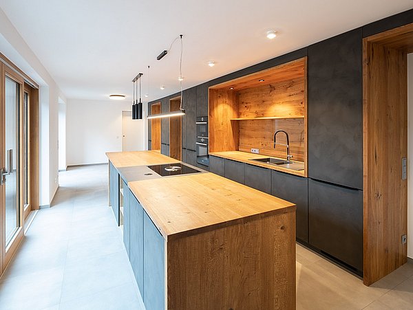 Foto, Innenansicht einer Küche mit Küchenzeile und Kücheninsel in Schwarz und Holz