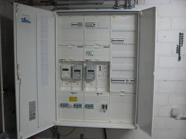 Foto, Geöffneter moderner Stromzählerkasten mit mehreren Zählern und Sicherungen